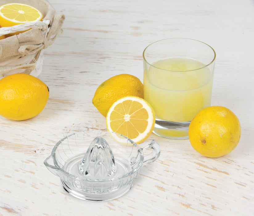 glass orange juicer on countertop with cup of orange juice